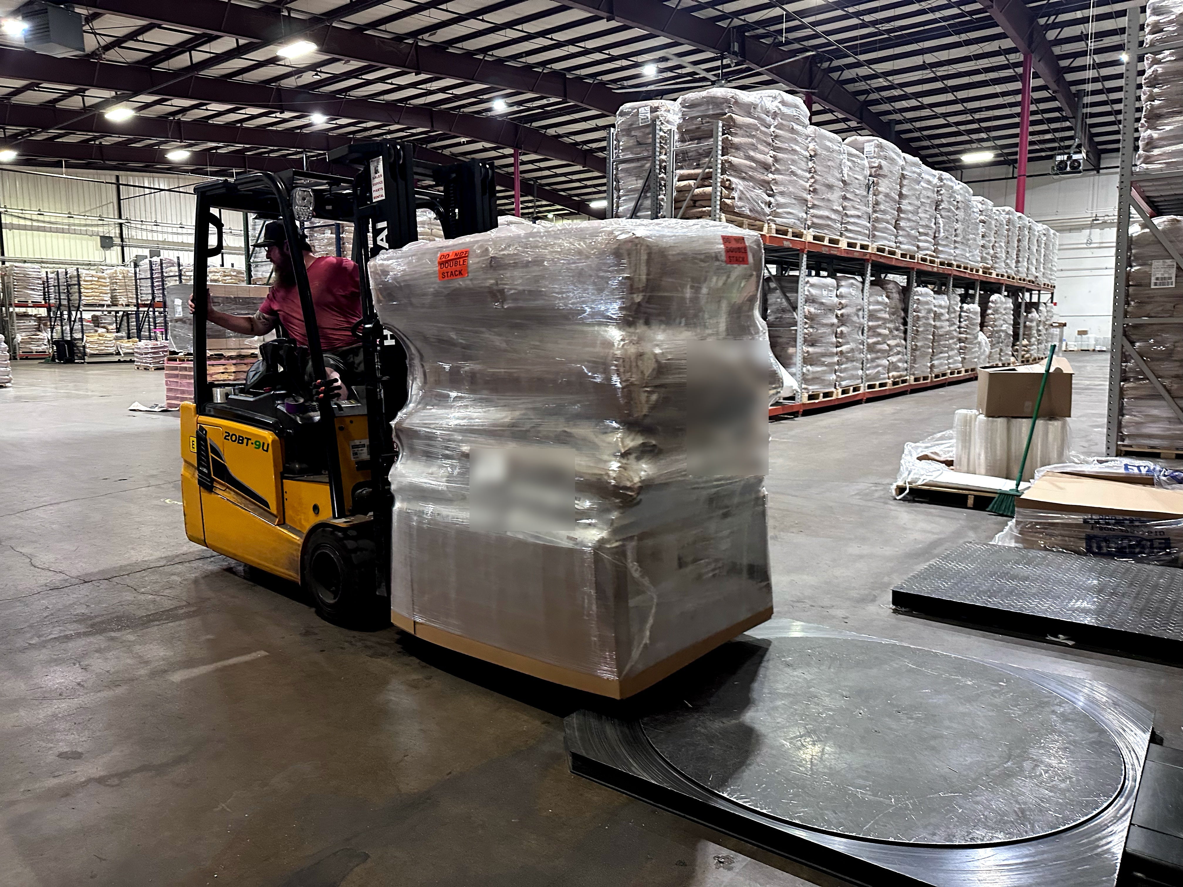 Forklift moving a shrink-wrapped pallet of brewing ingredients across the Pro Brew Supply warehouse floor