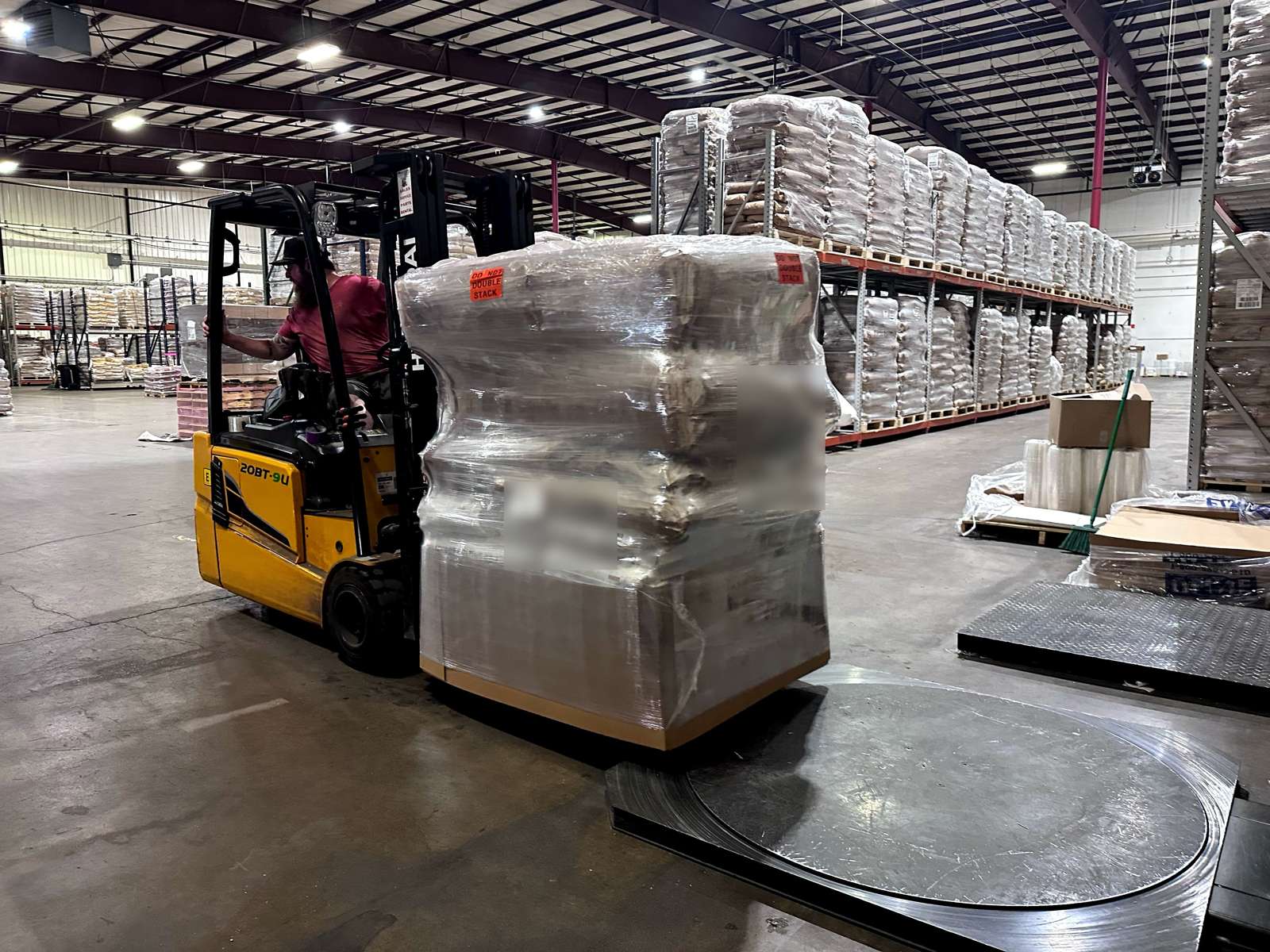 Forklift moving a shrink-wrapped pallet of brewing ingredients across the Pro Brew Supply warehouse floor
